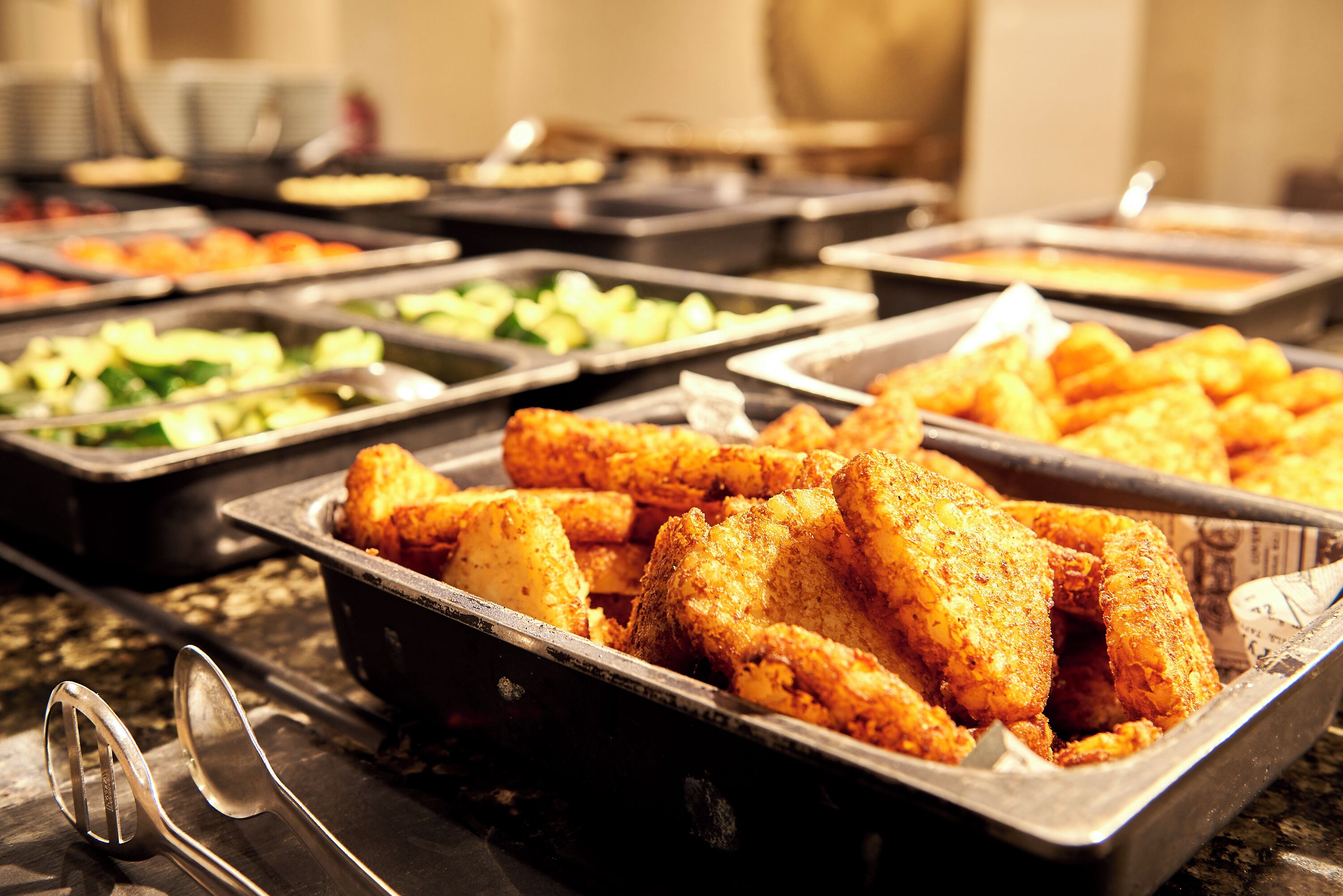 Un buffet proposant une variété de plats, notamment du poulet frit, des salades et d’autres mets.