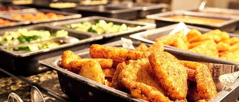 Un bufé con diversas opciones de comida, incluyendo pollo frito, ensaladas y otros platos.
