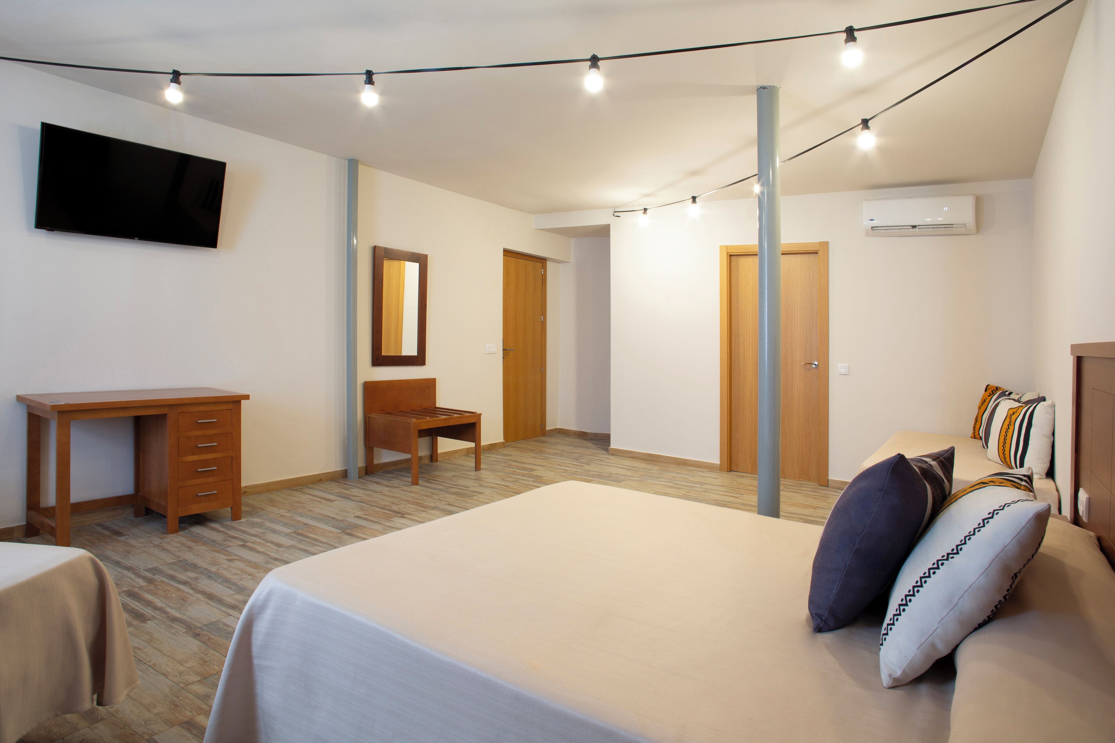 Een slaapkamer met een bed, een bureau, een stoel, een televisie en een kledingkast.