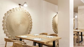A dining area with a round table, wooden chairs, and a textured wall decoration.
