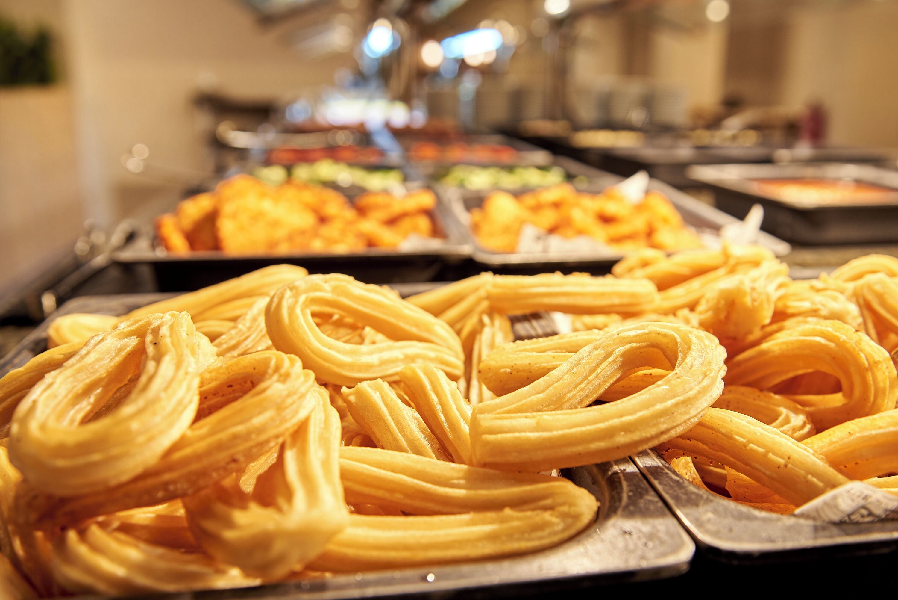Een buffet met verschillende gerechten, waaronder churros en andere gebakjes.