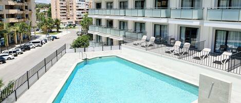 Un hotel con piscina, varios balcones y vistas del entorno.