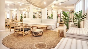 Un hall d’entrée spacieux avec un espace salon central, des meubles en bois et de grandes fenêtres.