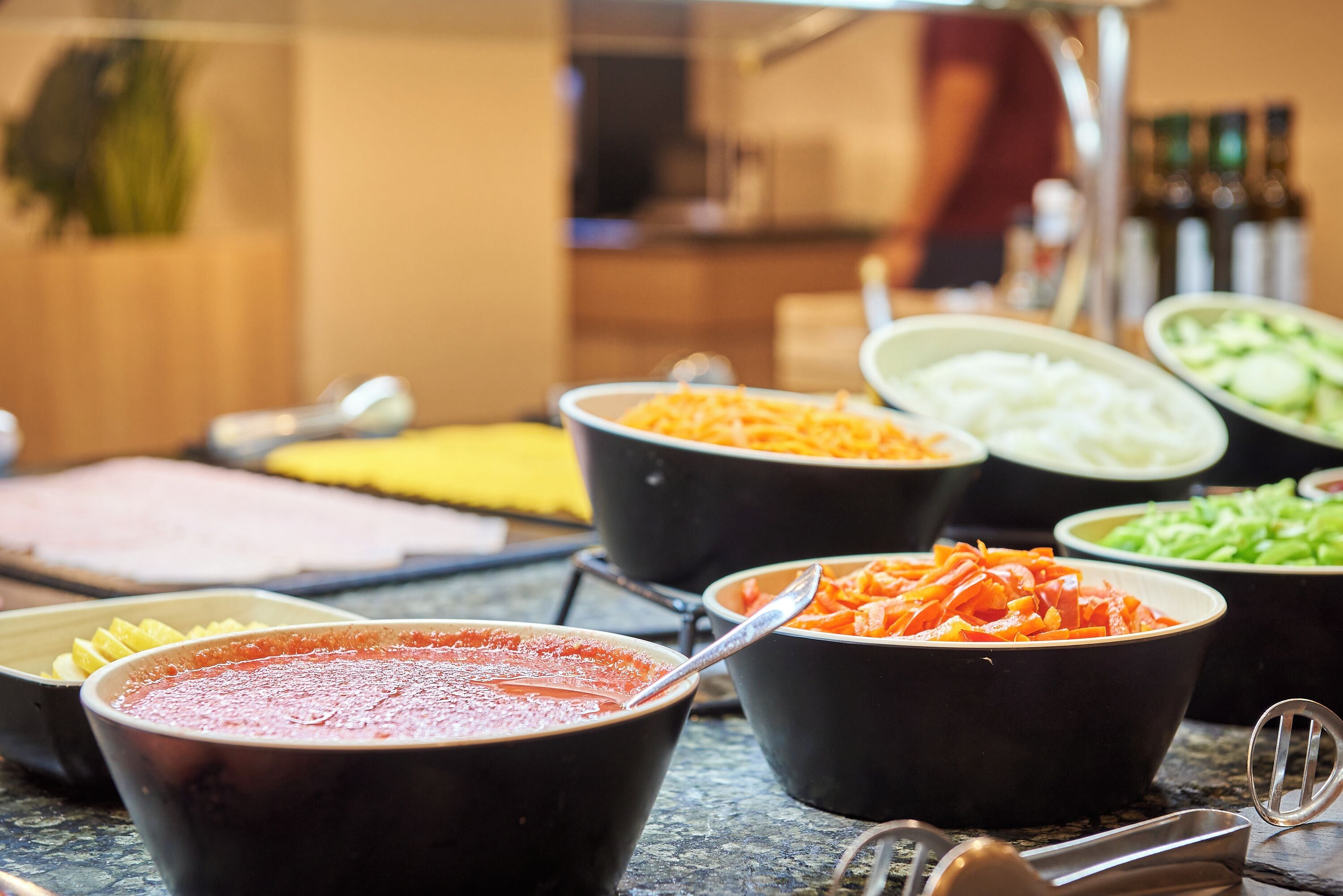 Una mesa de buffet con diversos platos, incluyendo pasta, verduras y salsa roja.