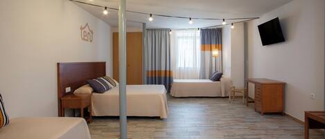 Habitación de hotel con dos camas, un escritorio, una silla, un televisor y una ventana con cortinas.