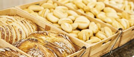 Une variété de pains et de viennoiseries présentés dans des plateaux en bois.