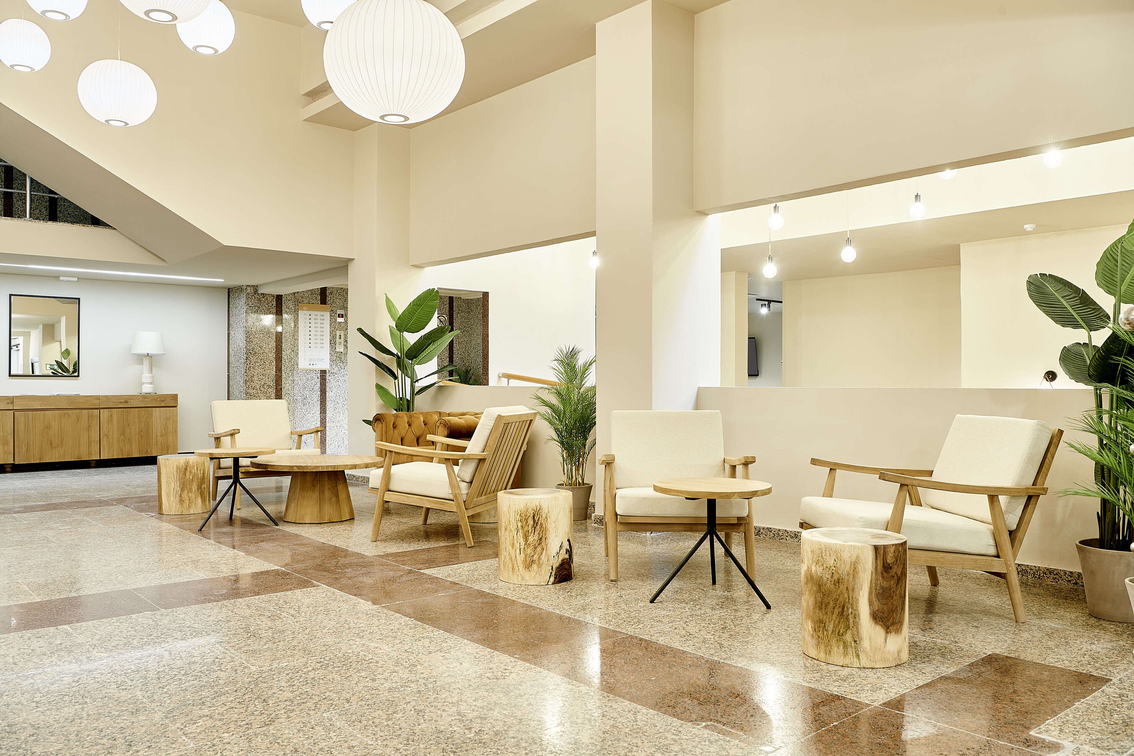 Un vestíbulo amplio con techo alto, mobiliario moderno y una combinación de iluminación natural y artificial.