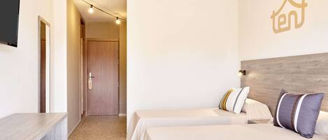 Une chambre d’hôtel avec deux lits, une tête de lit en bois, un bureau et un téléviseur.