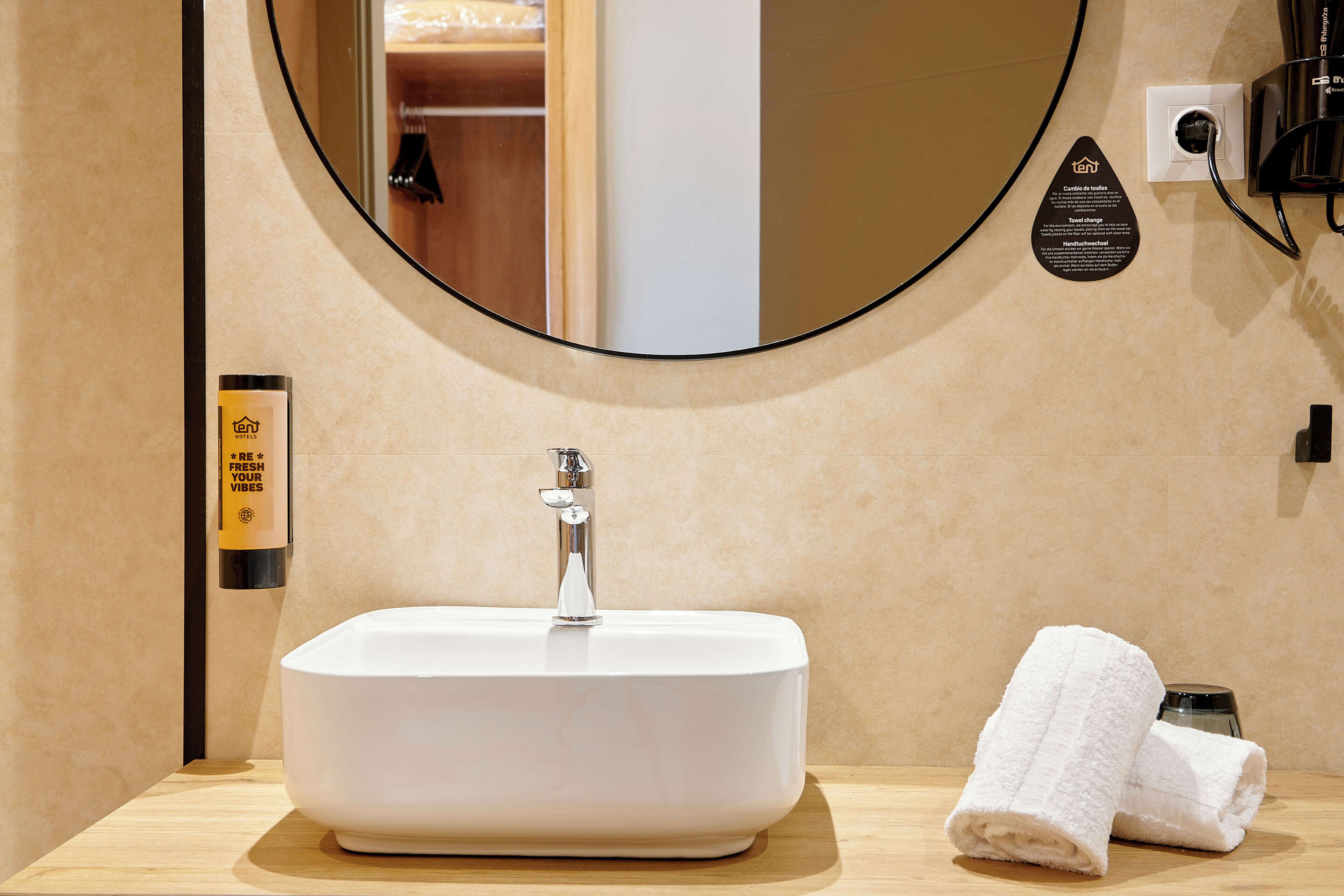 Une salle de bain avec un lavabo blanc, un miroir et une serviette posée sur le comptoir.
