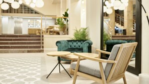 Un hall d’entrée moderne avec un canapé turquoise, des chaises en bois et un sol à motifs.
