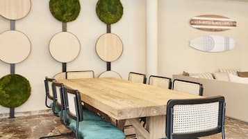 Un salón de conferencias con una mesa de madera, sillas negras con cojines verdes, y una pared decorada con paneles de madera circulares y detalles de musgo verde.