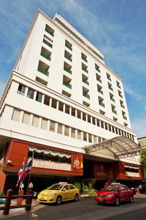 A multi-story hotel with a flat facade, a covered entrance, and a red and white color scheme. - Silom City Hotel (Bangkok)