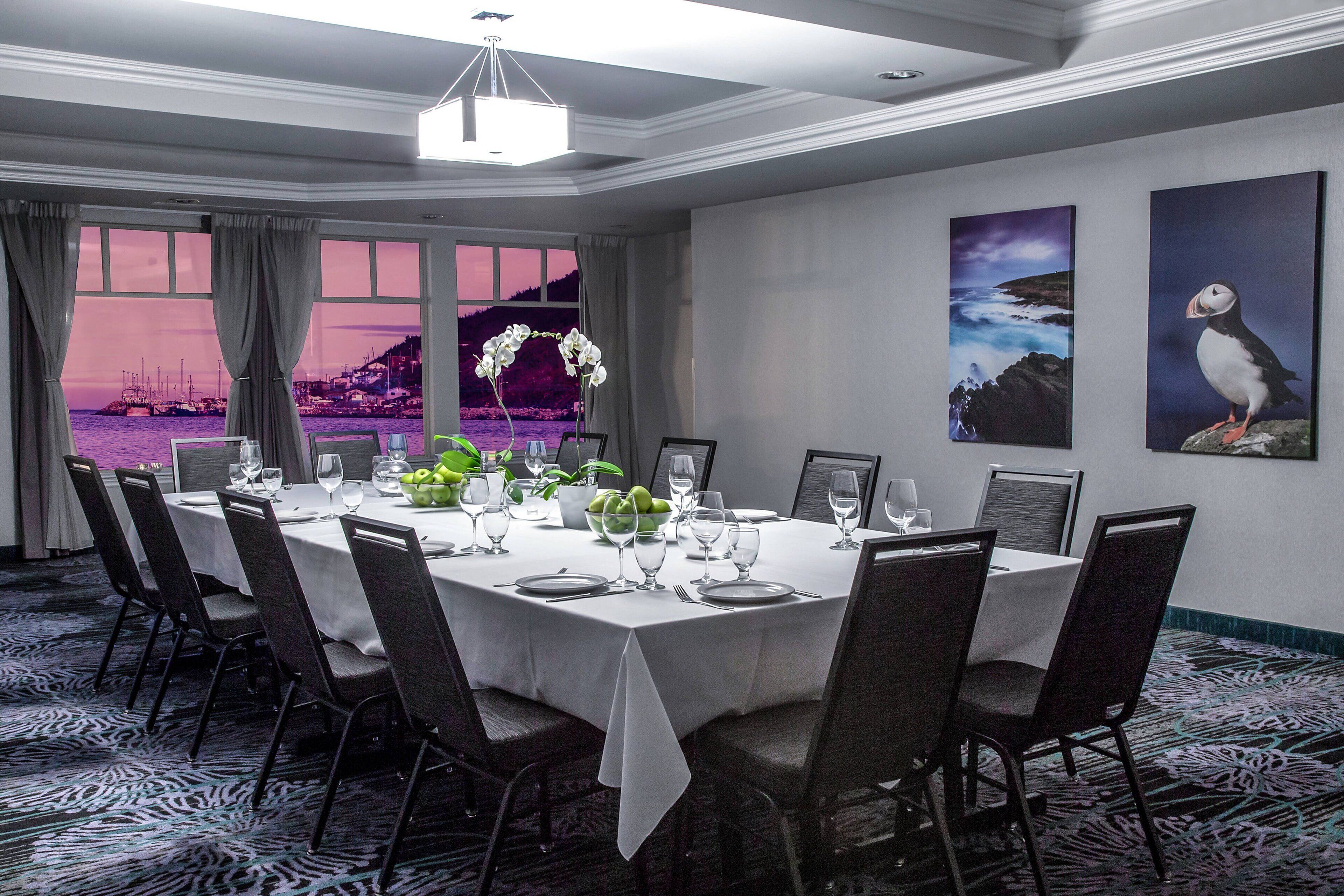 A dining room with a round table set for six, surrounded by chairs.