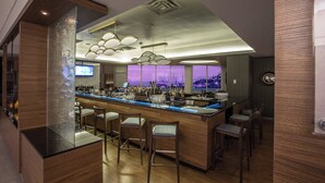 A modern bar area with a central island, bar stools, and a city view through large windows. - Courtyard by Marriott St. John's Newfoundland (St. John's)
