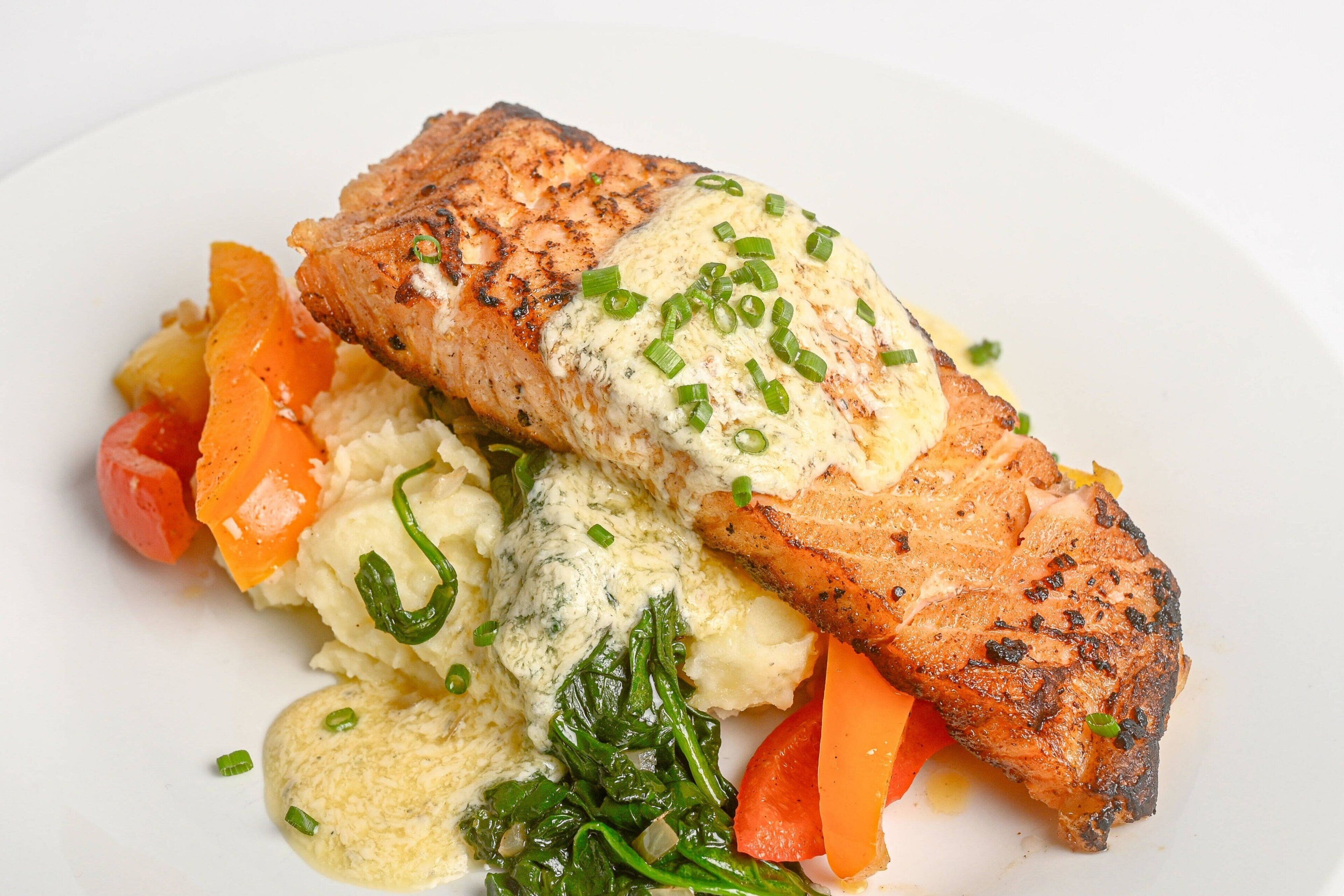 A plate with grilled salmon, mashed potatoes, and steamed vegetables.