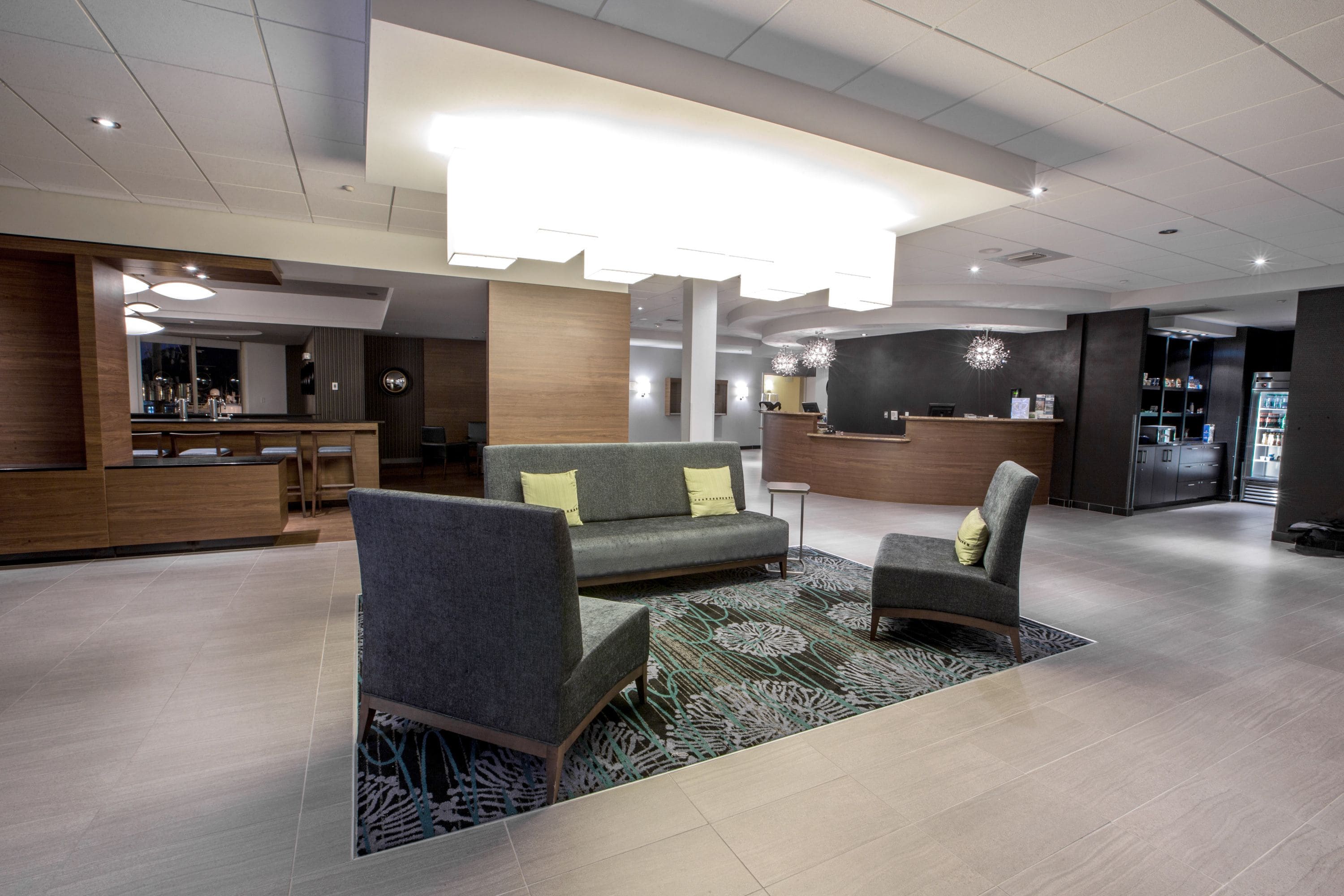 A modern lobby with a reception desk, seating area, and a bar.