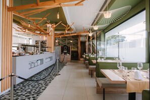 A modern restaurant interior with a central bar, seating area, and large windows. - Club Maspalomas Suites & Spa - Adults Only (San Bartolomé de Tirajana)