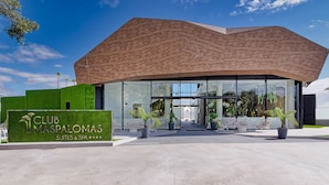 A modern Club Maspalomas building with a distinctive wooden roof and large glass windows. - Club Maspalomas Suites & Spa - Adults Only (San Bartolomé de Tirajana)