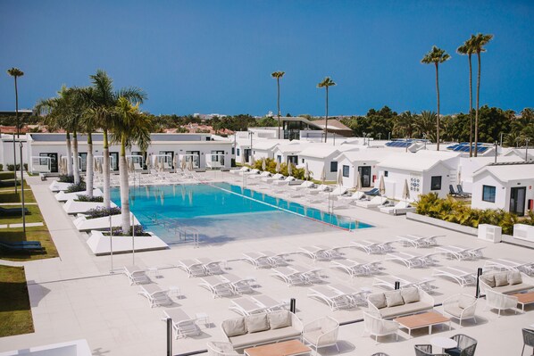 A poolside area with lounge chairs and umbrellas, a swimming pool, and palm trees. - Club Maspalomas Suites & Spa - Adults Only (San Bartolomé de Tirajana)