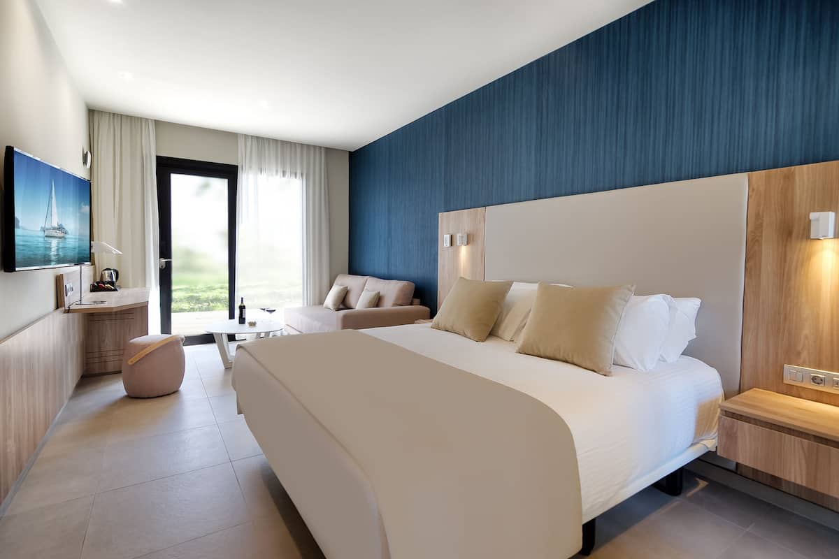 Ein modernes Hotelzimmer mit einem großen Bett, einer Couch, einem kleinen Tisch und einem Fernseher.