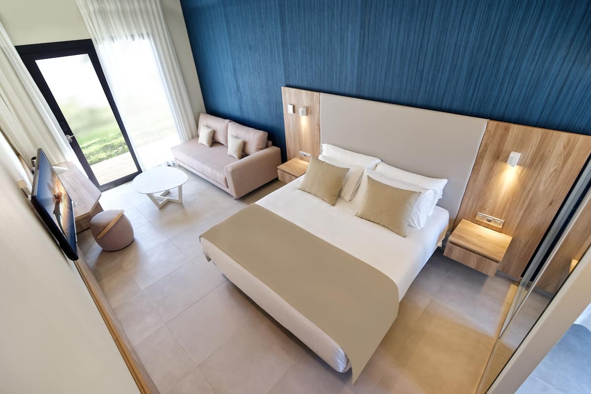 Ein modernes Hotelzimmer mit einem großen Bett, einer Couch, einem kleinen Tisch und einem Fernseher.