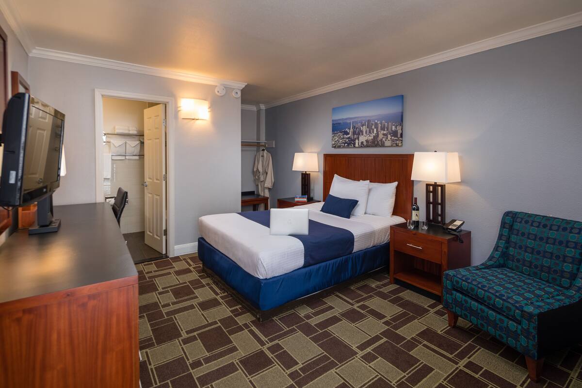 A hotel room with a bed, bedside lamps, a television, a desk, and a chair.