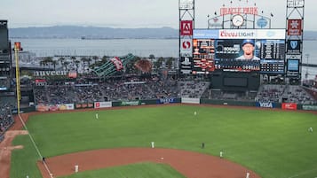 Un stade de baseball doté d’un grand tableau d’affichage, de panneaux publicitaires et offrant une vue sur la mer.