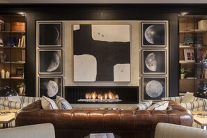 A modern living room with a fireplace, leather sofa, and framed artwork of the moon. - Hotel Casa Elliot (Barcelona)