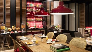 Un ambiente de desayuno con una mesa de madera, sillas de mimbre e iluminación colgante roja.