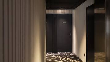 Un pasillo con piso estampado y una puerta oscura marcada con el número 101.