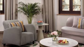 Una sala de estar moderna con un sofá gris, una mesita redonda con un centro de mesa floral y una planta en maceta.