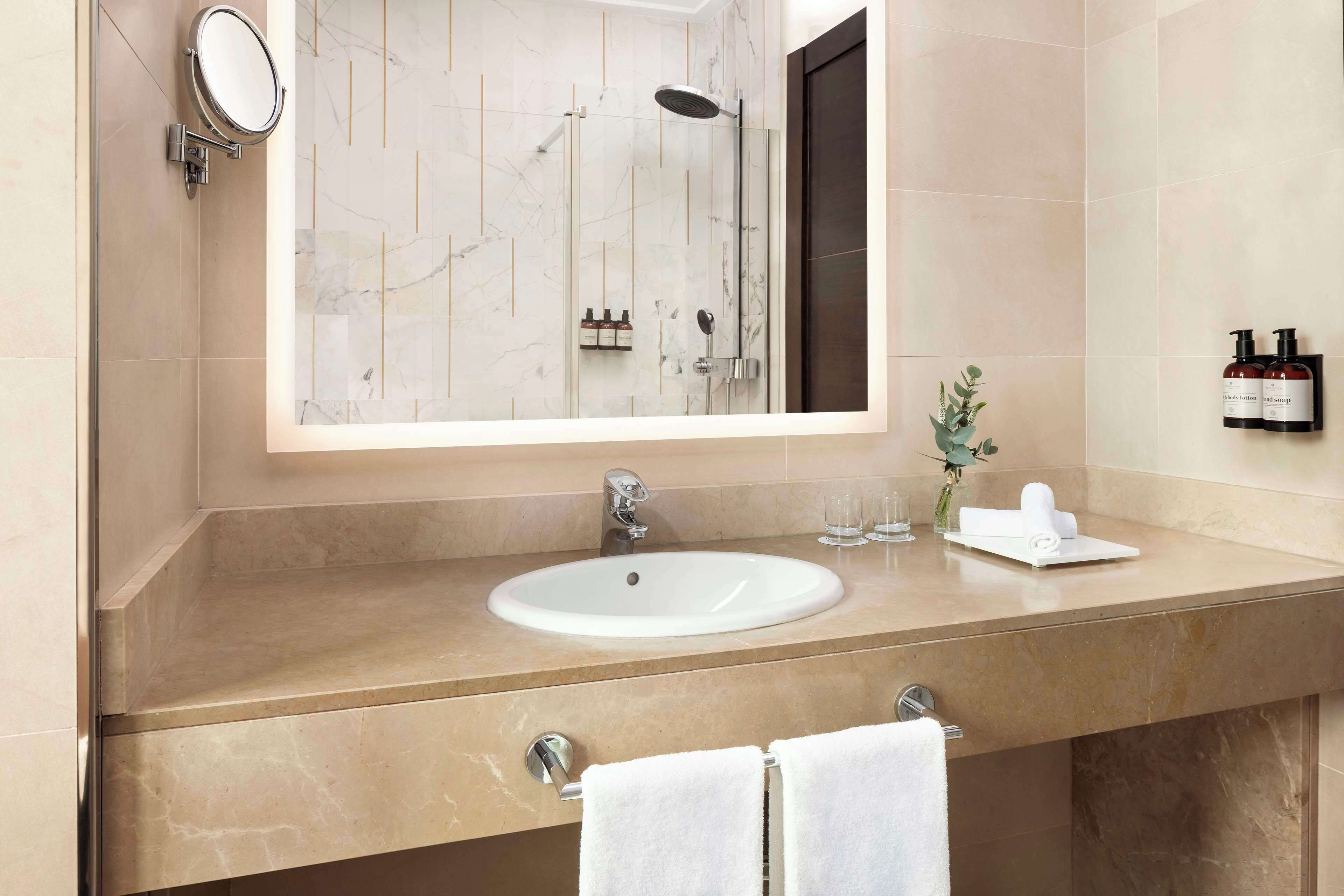 A modern bathroom with a large mirror, a sink, and a shower.