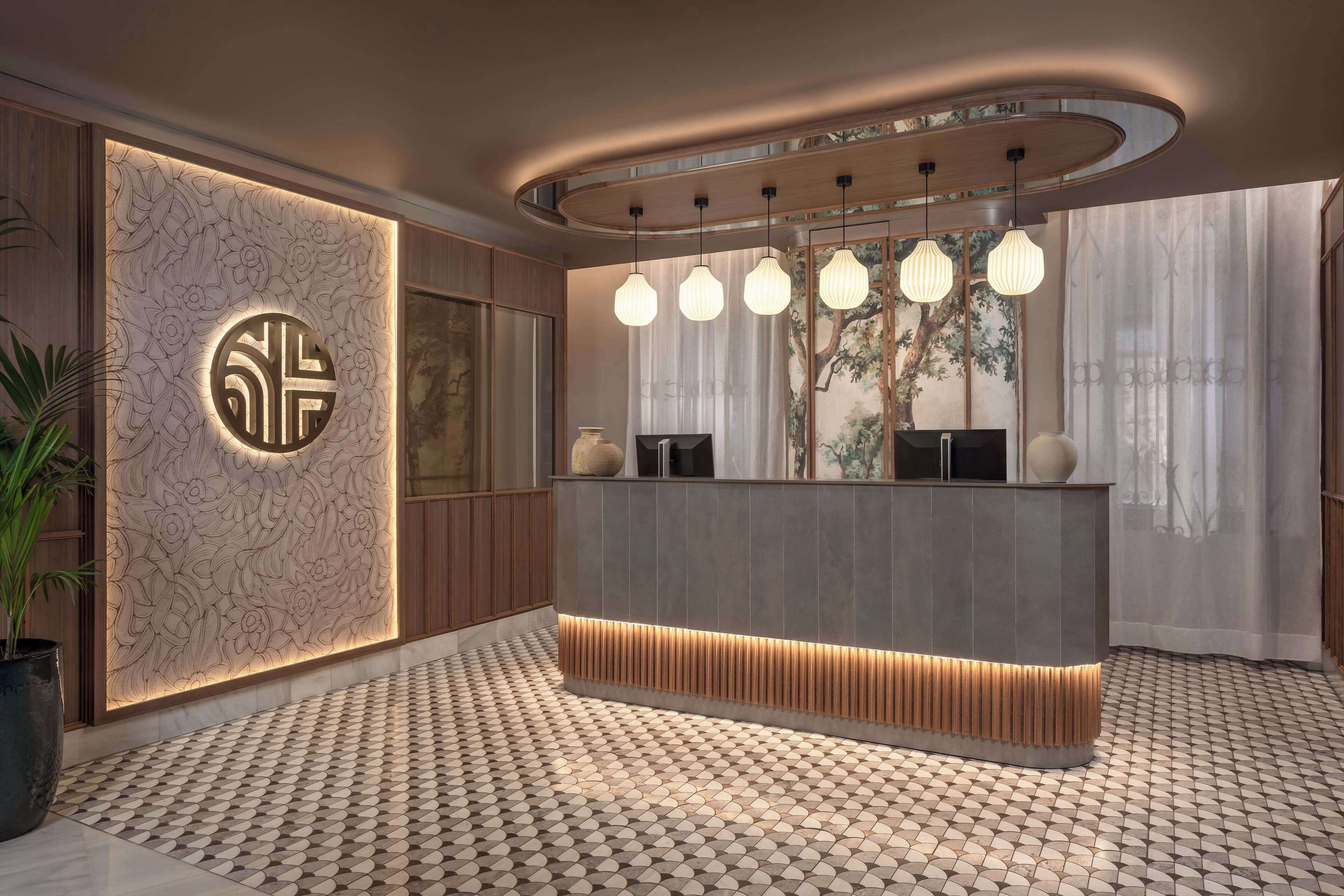 A modern reception area with a central desk, decorative wall paneling, and a patterned floor.