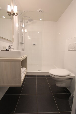 A modern bathroom with a shower, toilet, and sink.