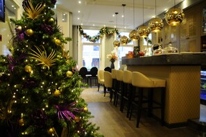 A modern hotel lobby with a Christmas tree, bar area, and seating.