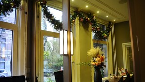 A room with a large window, a desk with a computer, and a vase with flowers. - Apple Inn Hotel (Amsterdam)