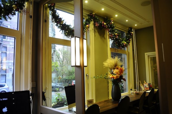 A room with a large window, a desk with a computer, and a vase with flowers. - Apple Inn Hotel (Amsterdam)