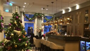 A bar area with a Christmas tree, bar stools, and a bar counter. - Apple Inn Hotel (Amsterdam)