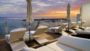 A rooftop lounge with white lounge chairs and umbrellas, overlooking a marina and sunset. - H10 Big Sur Boutique Hotel (Arona)
