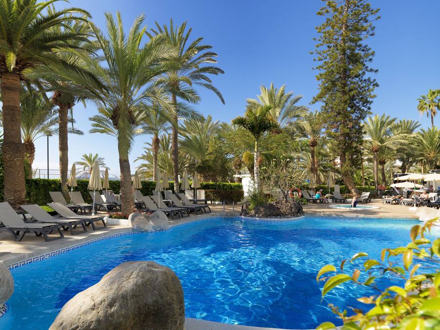 A pool with lounge chairs and palm trees.