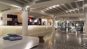 A hotel lobby with a reception desk, seating area, patterned floor, and modern decor. - H10 Big Sur Boutique Hotel (Arona)