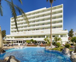 Un gran hotel con múltiples balcones, piscina y zonas de estar al aire libre.