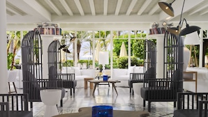 A modern lounge area with a patterned floor, white sofas, black chairs, and a blue table. - H10 Big Sur Boutique Hotel (Arona)