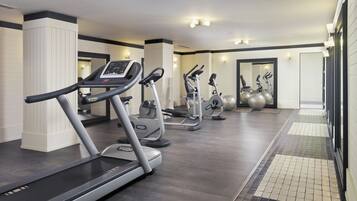 Un gimnasio con cintas de correr, elípticas y pelotas de ejercicio.