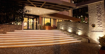 A hotel entrance with a stone facade, a staircase leading to the entrance, and a sign indicating a restaurant.