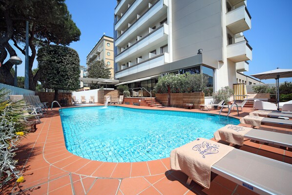 Una piscina al aire libre de temporada, sombrillas