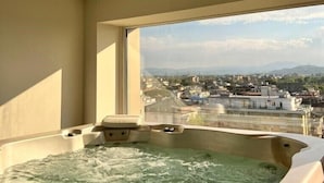 A hot tub with a city view through a large window. - National Hotel (Rimini)
