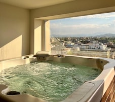 A hot tub with a city view through a large window.