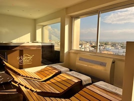 A sunlit room with wooden loungers and a view of the city.