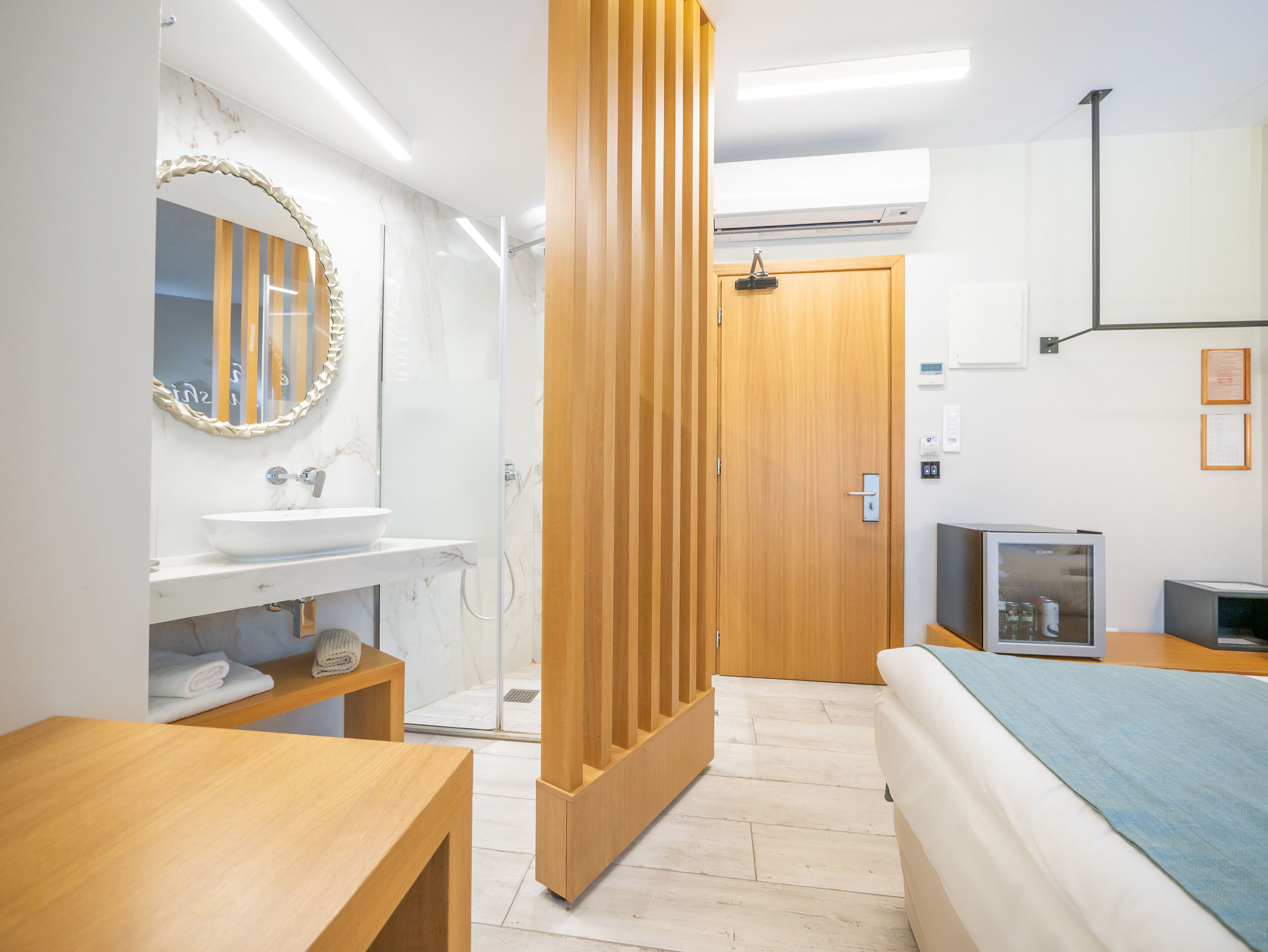 Un baño moderno con tocador de madera, un espejo grande y cabina de ducha de vidrio.